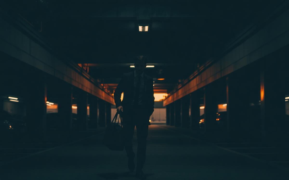 Professional carrying a gym bag through a parking garage at dusk